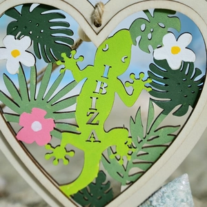 Detail of heart-shaped wooden wall hanging with gecko and tropical leaf engraving