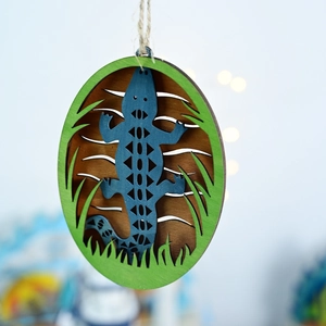 Detail of layered wooden lizard wall decor with deep blue silhouette and green foliage