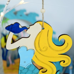 Macro shot of wooden mermaid pendant with yellow hair and blue shell for nautical decor