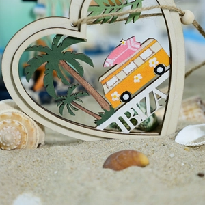 Detail of heart-shaped wood pendant with Ibiza bus and palm trees on beach sand