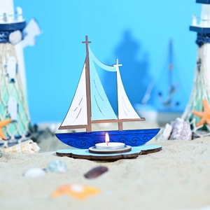 Détail du bougeoir voilier en bois avec bougie chauffe-plat sur décor de sable marin