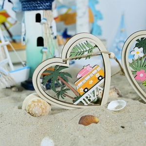 Detail of heart-shaped wooden Ibiza pendant with palm trees and surfing bus on sandy beach