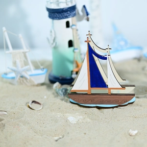 Mediterranean wooden sailboat model on sand with beach accessories and lighthouse
