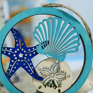 Close-up of wooden nautical hanging sign featuring starfish and scallop in blue tones