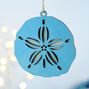 Macro detail of a blue wood sand dollar ornament with laser-cut star and rustic hemp rope