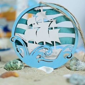 Wooden sailboat hanging plaque in nautical ocean style with jute rope on beach
