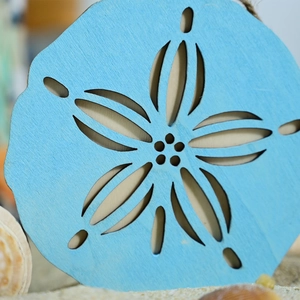 Macro view of light blue nautical wooden star ornament on a sandy beach with shells