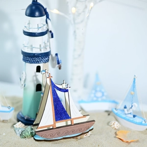 Detail of wooden Mediterranean sailboat model on sand with beach nautical decor