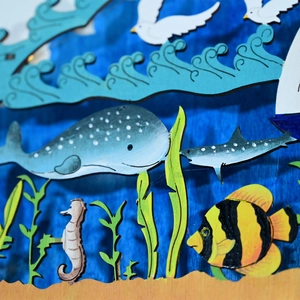 Dettaglio di balena in legno tagliata al laser e creature marine con texture blu