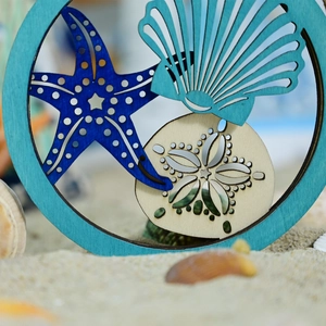 Detail of wooden coastal ornament featuring laser-cut starfish and seashell layers