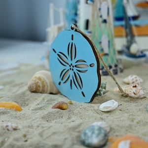 Detailed close-up of blue ocean-themed wooden star cutout hanging on beach sand