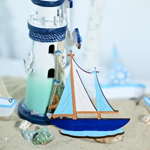 Mediterranean nautical wood sailboat and lighthouse decor on a sandy beach setting
