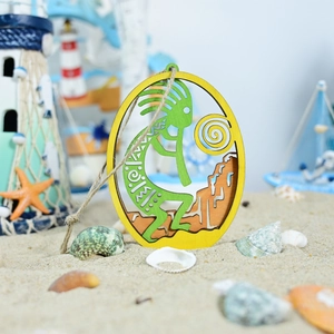 Coastal wooden Kokopelli ornament with layered design on a beach sand background