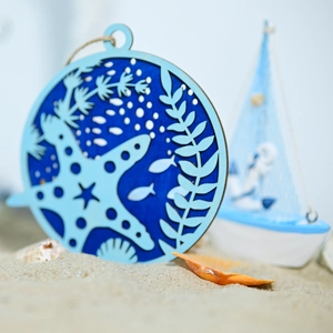 Detail of round wooden marine ornament featuring layered starfish and sea grass elements