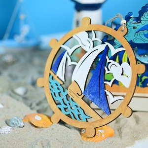 Detail of wooden nautical ship wheel hanger with sailboat scene on sandy beach