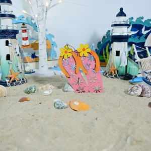 Detail view of pink and orange wooden flip-flop beach wall decor on sand background