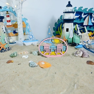 Küstenszene mit hölzernen Liegestuhl-Plakette auf echtem Sand vor Meereshintergrund