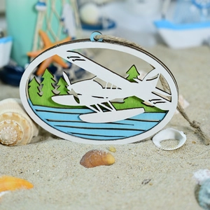 Detail eines Holzanhängers mit Wasserflugzeug, Seesternen und Muscheln am Sandstrand