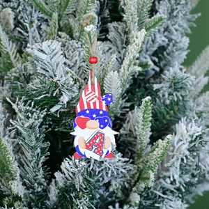Detail of USA Independence Day gnome wood tag with letter A on a snowy pine branch
