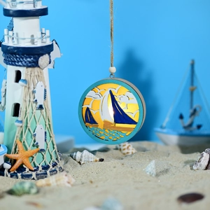 Close-up of LED wooden ocean ornament with carved sailboats and warm yellow light