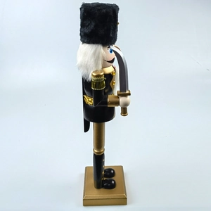 Side view of black and gold nutcracker soldier with plush hat and silver sword detail