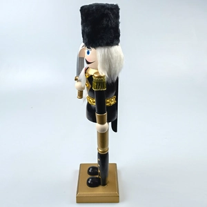 Detail of a vintage black and gold Nutcracker soldier with sequined uniform and saber