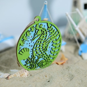 Detail of wooden ocean wall decor featuring hollow sea horse and shell in green and blue
