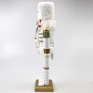Detailed side view of a white and gold Nutcracker soldier with plush hat and silver sword