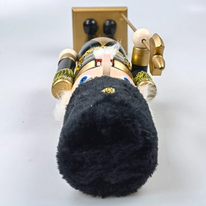 Close-up of black and gold wooden nutcracker soldier with fluffy hat and golden halberds