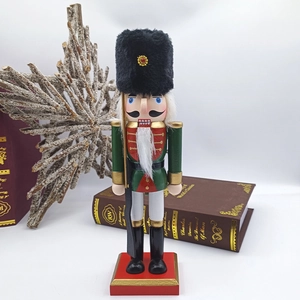 Detailed view of a 25.5cm wooden nutcracker soldier in green uniform with gold tassel accents