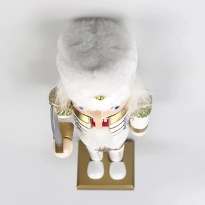 Close-up of a 30cm white and gold nutcracker king with plush hat and golden tassels