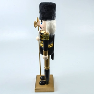 Detail of wooden nutcracker soldier in black and gold uniform with golden axe