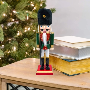 Detailed view of a 25.5cm wooden nutcracker soldier standing near a festive Christmas tree