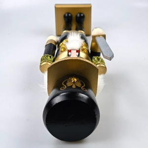 Top-down macro of a black and gold Nutcracker ornament with silver sword detail