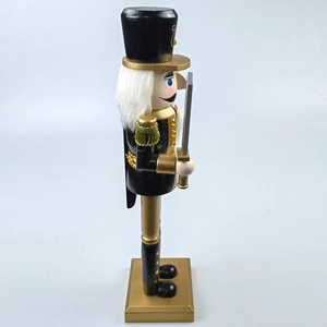 Detailed side view of wooden Nutcracker soldier in black and gold with a silver sword