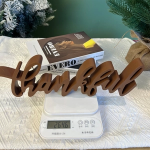 Detail shot of a brown wooden Thankful letter sign on a scale weighing 264.6 grams
