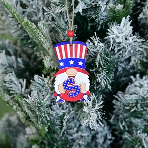 Patriotic wooden gnome ornament with USA flag patterns hanging on a snowy branch