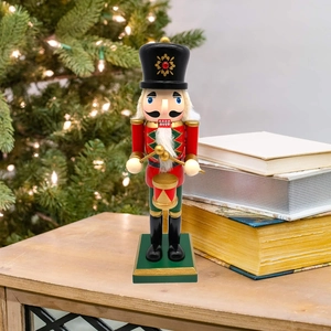 Close-up of wooden nutcracker soldier with drum on wooden table with holiday backdrop