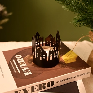 Nordic black metal hollow house candle holder on a book with festive pine decoration