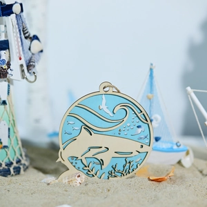 Detail of laser-cut wooden shark hanging ornament on beach sand with nautical decor