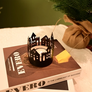 Detail of black metal hollow house candle holder with lit tealight on a book