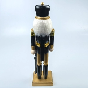 Detail of black and gold wooden nutcracker soldier with plush beard and stable base