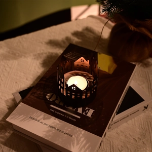 Detail of black metal hollow city architecture candle holder on decorative books