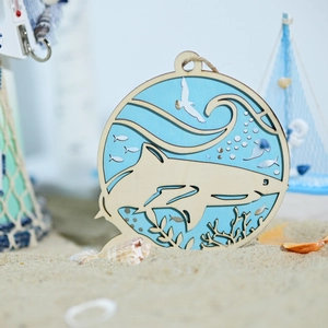 Detail of wooden ocean wall decor with shark and wave elements on sandy background