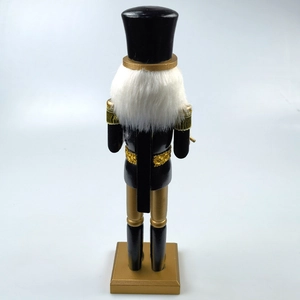 Back view of a classic black and gold wooden nutcracker with long white fur and tassels