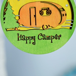 Detail of wooden multi-layer ornament with camping scene and Happy Camper engraving
