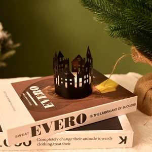 Detail of black hollow metal house candle holder with tea light on decorative books