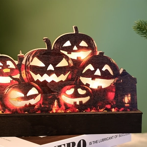 Close-up of Halloween wooden pumpkin decor with internal LED lights on a book base