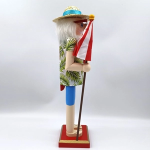 Hawaiian Nutcracker in palm leaf shirt holding a striped parasol on red base