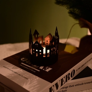 Close-up of black metal Nordic house candle holder silhouette on books with warm lighting